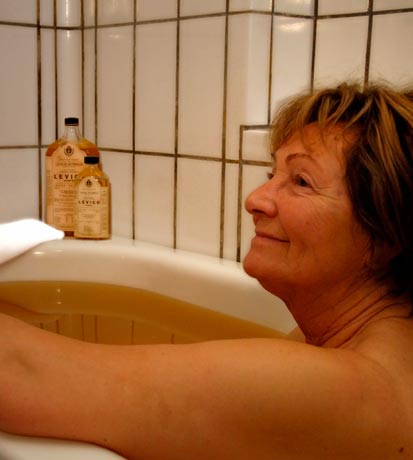 Una signora in una vasca da bagno con olio per un trattamento