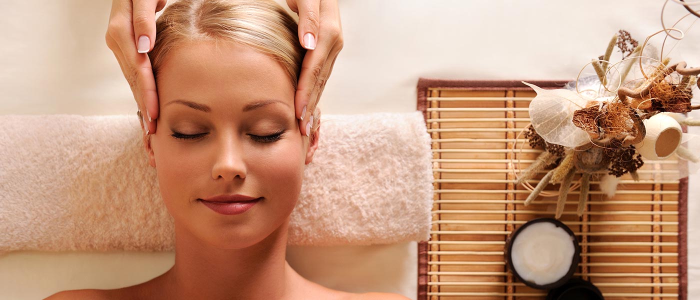 una giovane signora si fa fare un massaggio al viso in un hotel wellness